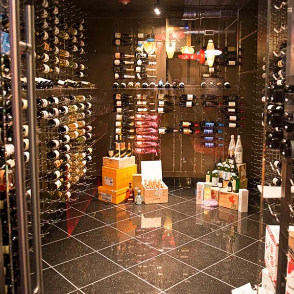 A large, dark wine cellar with bottles on racks, boxes on the floor, and airplane-shaped lights.