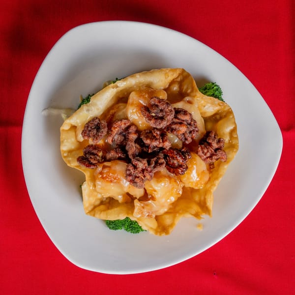 Crispy fried wonton bowl filled with shrimp, glazed walnuts, and broccoli on a white plate.