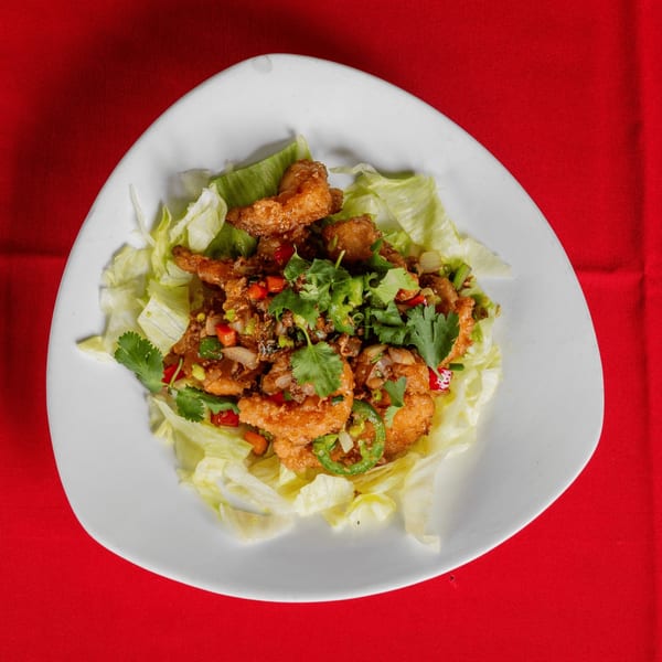 Crispy fried shrimp with chopped peppers, onions, and cilantro, served on a bed of lettuce.